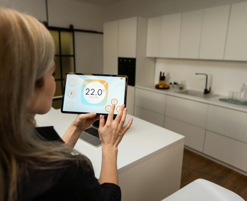 Iot Smart Home Concept - rear view of woman ask digital tablet to set temperature of air conditioner